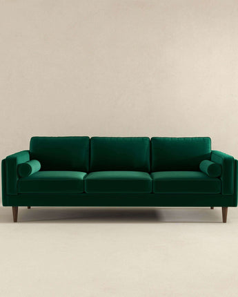 Mid-century modern dark green sofa with a minimalist design.